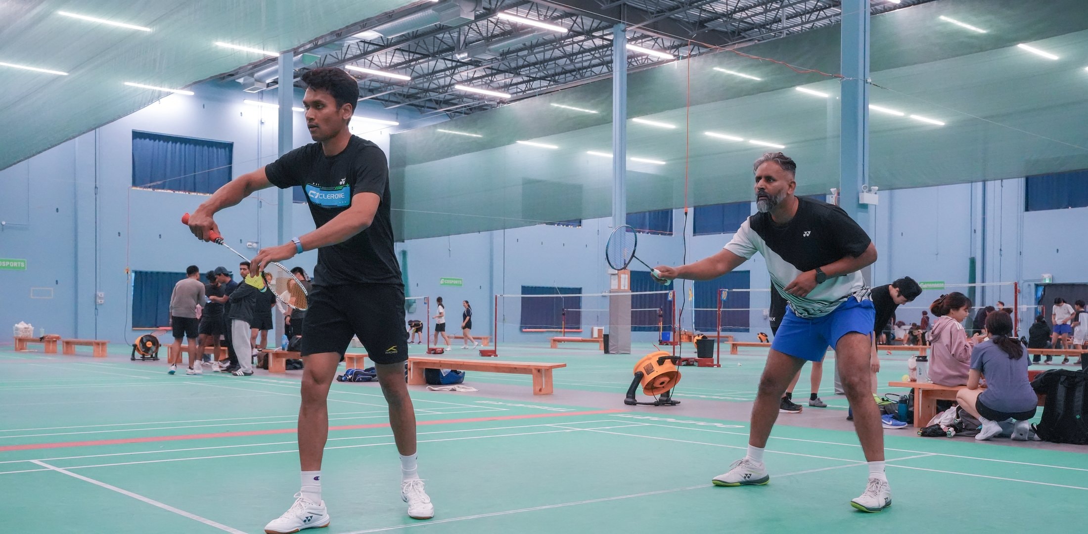 InspireBC Men's & Women's Badminton Tournament 2026 — a doubles pair ready to receive serve at CoSports